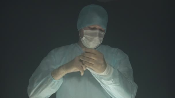 疲れた外科医は、病院での手術や手順の後に彼の手袋、マスク、帽子を脱ぐ. — ストック動画