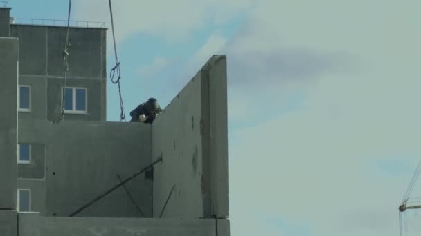 Bouw van residentiële gebouwen. Werknemer lassen een structuur. Vastgoedmarkt. Bouwers werken op de bovenste verdieping. Bewolkt en bewolkte weersomstandigheden — Stockvideo