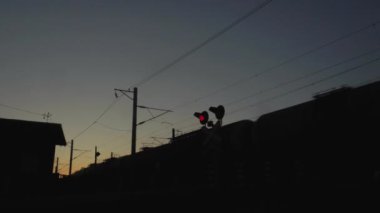 Kavşakta kırmızı demiryolu trafik ışığı, bir yük treninin arka planına karşı, mavi gökyüzü