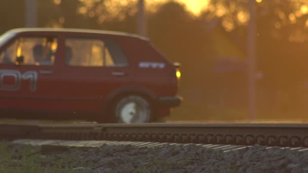 Автомобили, движущиеся через железнодорожный переход на фоне солнечного заката, опасность на железной дороге, фон, копировальное пространство — стоковое видео