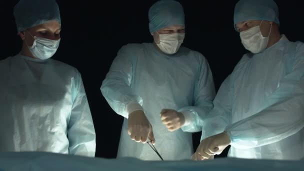 Οι χειρουργοί γελούν κατά τη διάρκεια της λειτουργίας ή της διαδικασίας. Ο γιατρός με τη δική του. Οι βοηθοί βοηθούν στην εγχείρηση στο νοσοκομείο. Κοπή ασθενών ιστών — Αρχείο Βίντεο