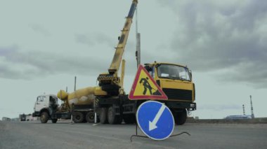 İşçiler yol boyunca otomobil vinç ile sokak Lambası ile bir direk yükleyin. İş makineleri, beton veya çimento karıştırıcı taşıma kamyonu çalışma alanındadır. Mühendisler otoyolda sokak lambası kurdular