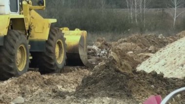 Yol yapım aşamasında toprakla yükleme ve boşaltma işlerini yürütmek için şantiyede bıçaklı veya mühendislik aracı çok amaçlı makine li tek kova tekerlekli yükleyici traktör