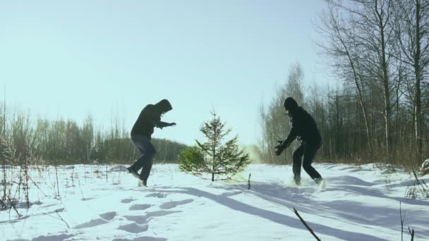 Двое мужчин танцуют и дурачатся в зимнем поле вокруг елки, концепция встречи новогодних праздников, замедленная съемка — стоковое видео