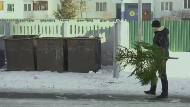 Mann wirft nach Silvester in der Stadt einen Weihnachtsbaum in Mülleimer in der Nähe des öffentlichen Recyclinghofs Konzept Ende der Feier. Zeitlupe — Stockvideo