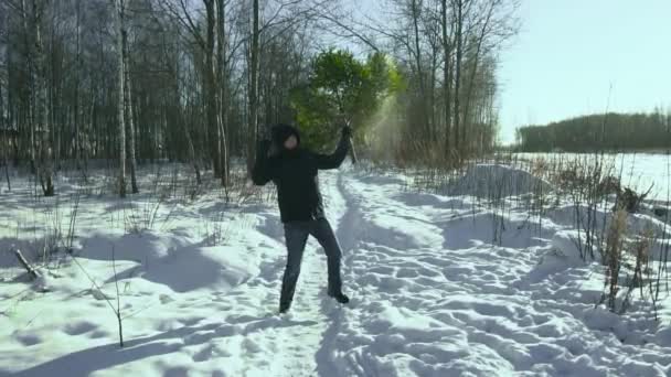 Hombre divertido bailando con árbol de Navidad en la mano en el invierno en el bosque antes de año nuevo en la ciudad. Concepto de inicio de la celebración. Movimiento lento — Vídeo de stock