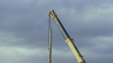 Yol boyunca sokak lambası olan bir direk yerleştiren otomobil vincini kapatın. İnşaat makineleri çalışma sahasında. Mühendisler otoyola lamba direği kurdular