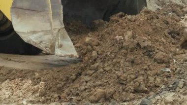 Bıçaklı bir traktör kovasında toprak topluyor. Karayolu inşaatı sırasında yükleme ve boşaltma işlerini gerçekleştirmek için inşaat sahasında çok amaçlı mühendislik aracı sürüşleri