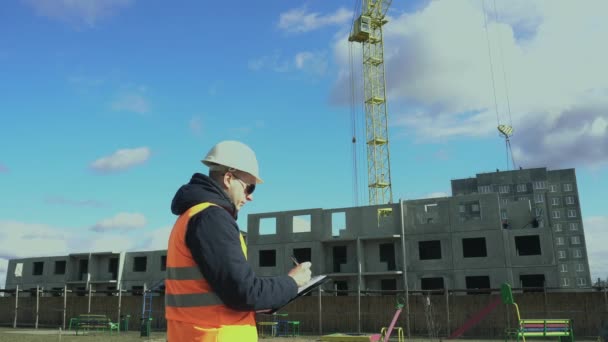 Výstavba obytných budov Strojník zapisuje data do schránky. Trh nemovitostí. Tvůrce zkontroluje informace v poznámkovém bloku. Šéf nebo šéf vypadá jako technický ukazatel. — Stock video