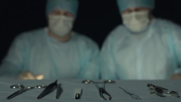 Хірурги беруть інструменти і починають операцію або процедуру. За межами фокусу для тла. Лікарі з скальпелем, хакером або фосфором готові почати розрізання тканин пацієнта в лікарні . — стокове відео