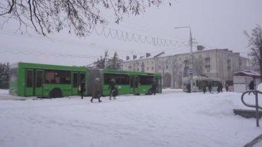İnsanlar otobüs durağında toplu taşıma bekliyor. Kış şehri, kar yağıyor, yavaş çekim Bobruisk, Belarus - 14 Ocak 2019
