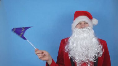 Mavi arka planda Avrupa Birliği bayrağını sallayan sakallı Noel Baba kostümlü bir adam. Dünyada yeni yıl tatili kavramı