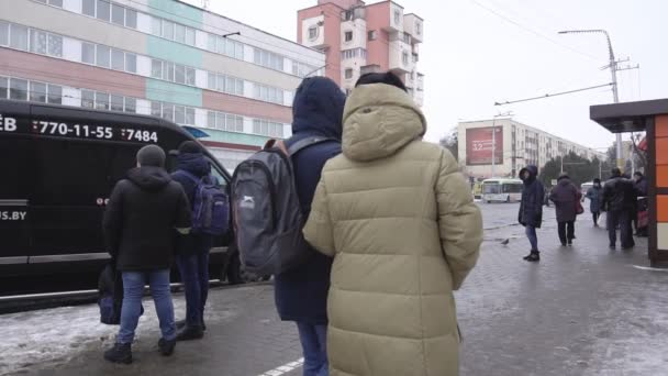 La gente sta aspettando i mezzi pubblici ad una fermata dell'autobus. Città invernale, nevica, slow motion BOBRUISK, BELARO - 14 GENNAIO 2019 — Video Stock