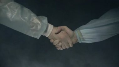 Doktorlar ameliyatın başarıyla sonuçlanmasından sonra el sıkışıyor. İlaçlar. Dumanlı siyah arka plan. Hayat kurtar ya da öldür kavramı. Ameliyat ve ameliyat masası. Yavaş çekim