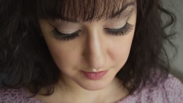 Closeup girlss face with closed eyes and long false lashes. Beautiful brunette female model with gorgeous makeup and black curled hair. Natural and clean skintone. — Stock Video