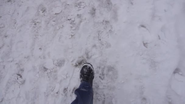 Um homem caminha na neve e tira as pernas da câmera, fundo, inverno, câmera lenta, calçados — Vídeo de Stock