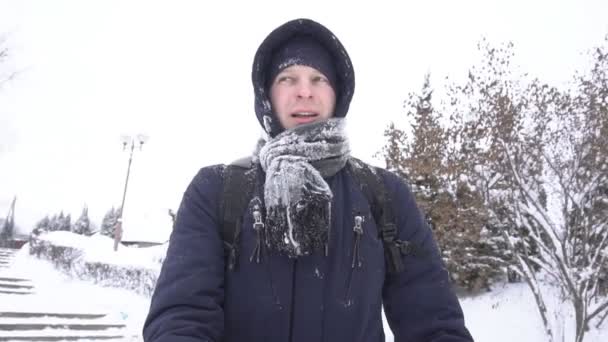 Jonge blanke man wandelen in een besneeuwde stad, video portret, slow motion — Stockvideo