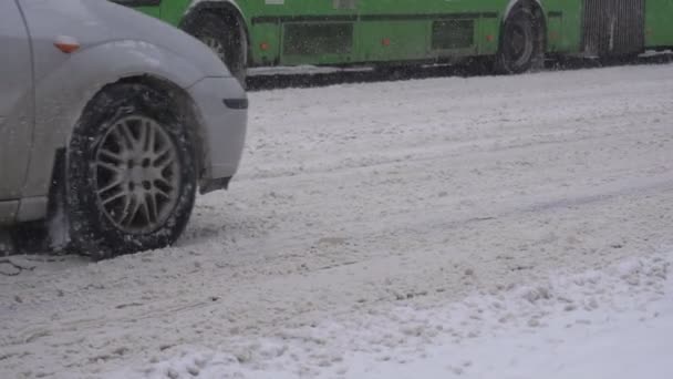 Auto 's en voertuigen rijden op een besneeuwde weg in de stad, reagentia ruimen de weg in de winter, achtergrond, slow motion, close-up — Stockvideo