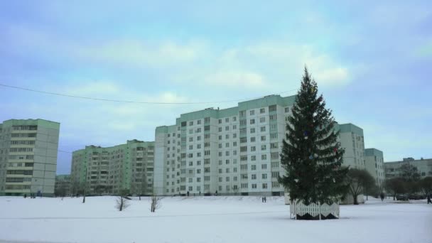 A díszített karácsonyfa az orosz város egy szegény lakónegyedében van szilveszterkor, délután. A városiak sétálnak és lazítanak. Az ünnepek és ünnepségek kezdetének koncepciója. — Stock videók