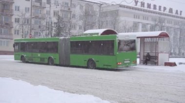 İnsanlar otobüs durağında toplu taşıma bekliyor. Kış şehri, kar yağıyor, yavaş çekim Bobruisk, Belarus - 14 Ocak 2019