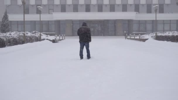 Un uomo in citta 'cammina per strada sotto la neve, al rallentatore — Video Stock