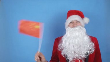 Mavi arka planda Çin bayrağı sallayan sakallı Noel Baba kostümlü bir adam. Dünyada yeni yıl tatili kavramı