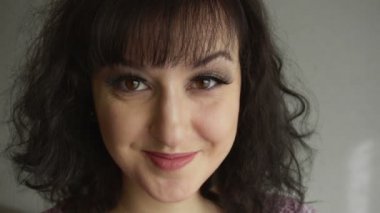 Gülümseyen, uzun takma kirpikli, kahverengi gözlü ve siyah saçlı tatlı esmer kız kameraya bakıyor. Moda makyajlı güzel bir kadın model. Doğal ve temiz ten rengi.