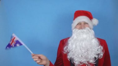 Mavi arka planda Avustralya bayrağı sallayan sakallı Noel Baba kostümlü bir adam. Dünyada yeni yıl tatili kavramı