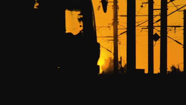 El autobús de pasajeros se mueve a través del cruce del nivel del ferrocarril en la puesta del sol. Fin de la jornada laboral, las personas viajan en transporte público desde el trabajo a casa. Peligroso tramo de carretera para accidente de tren o catástrofe — Vídeo de stock