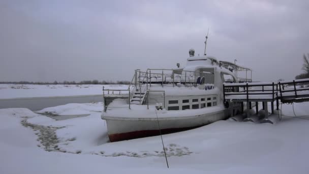 Das schneebedeckte alte Schiffsboot liegt im Winter tagsüber an der Mole. Schiff sowjetischer Kutter wartet auf Passagiere für Sommerspaziergänge auf dem Fluss — Stockvideo