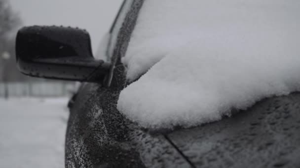 Kar kışın kar yağışında arabaların kaputuna düşer. Trafik ve kar fırtınası için kötü hava koşulları. Seyahatler için tehlike. Zemin yolundaki camsı kara buz. Karla kaplı otomobil bahçede. — Stok video