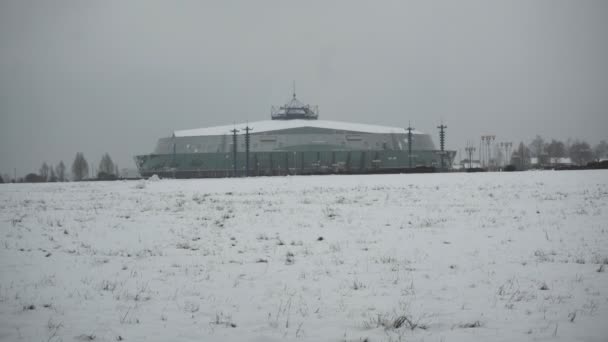 Architektoniczny budynek wygląda jak Ufo w zimowe opady śniegu w ciągu dnia. Nowoczesna hala hokejowa. Strzelanina ręczna. Złe warunki pogodowe na wycieczki, śnieżyca. dziwnie wyglądający budynek — Wideo stockowe