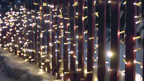 Christmas flashing blinking garland on the fence, night led decoration lighting, New year eve. Concept of beginning of holidays and celebrations. Background for copy space and text place — ストック動画