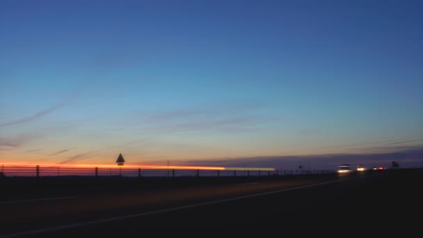 Timelapse verkeer op een landweg 's nachts op de Zonsondergang. Auto 's met koplampen gaan in de zomer op de snelweg. Reizen en toerisme concept. Naleving van de snelheidslimietmodus. Natuur en horizon — Stockvideo