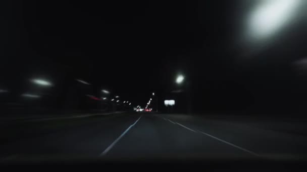 Timelapse, вид з вікна лобового скла. Автомобіль проходить через місто вночі на головній вуличній дорозі. Вітрове скло. Швидкість, трафік. Концепція подорожі. Автомобілі з фарами на шосе в місті — стокове відео