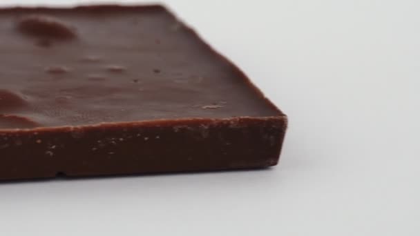 Macro tiro de barra de chocolate de leite com amêndoas inteiras nozes está no fundo branco sem pacote. Doce cacau deliciosa sobremesa. Isolado. Calorias e doces, açúcar. Conceito de dieta e alimentos não saudáveis — Vídeo de Stock