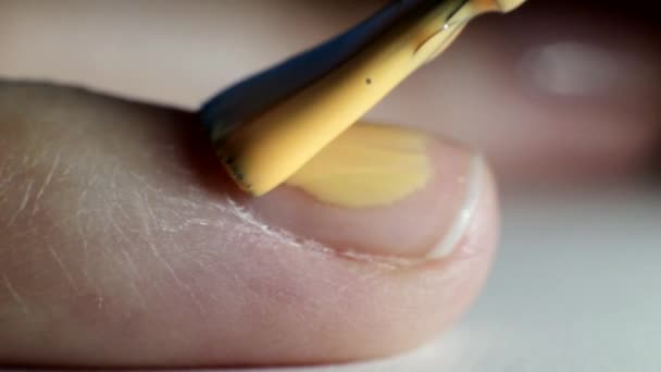 Дівчина робить манікюр на нігтях, наносить апельсиновий лак для нігтів, салон краси, макро — стокове відео
