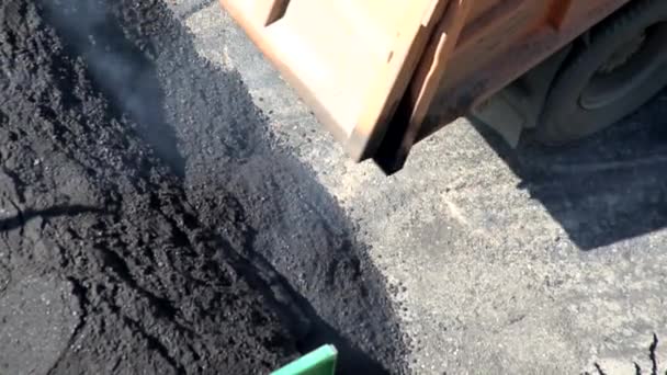 Ein Muldenkipper schüttet Asphaltbetongemisch in einen Fertigerbunker für Straßenreparatur, Industrie. Spezielle Straßenausrüstung, Arbeit — Stockvideo