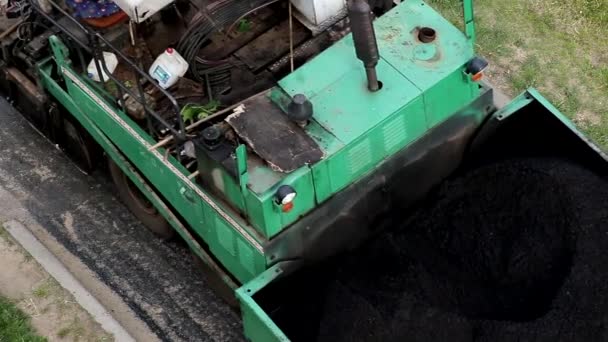 Ein Asphaltfertiger legt neuen Asphalt auf eine alte Straßenreparatur. Spezielle Straßenausrüstung, Industrie, Nahaufnahme — Stockvideo