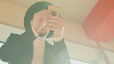 Siyah takım elbiseli ve şapkalı adam Yahudi ya da İtalyan mafyasına benziyor. Düşük açı, alt görüş. İnsan akıllı telefon ekranına bakar ve kendi ilişkilerine karar verir. Sakallı ve bıyıklı bir iş adamı.