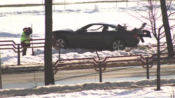 Зламана машина після аварії стоїть на боці вулиці взимку, на задньому плані. — стокове відео