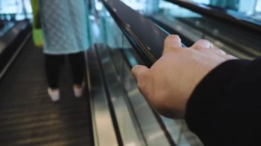 Erkekler, alışveriş merkezinde yürüyen merdivenlere tırmanırken tırabzanlara tutunuyor. Seyahat konsepti. Adam metrodan, havaalanından, tren istasyonundan çıkıp çıkışa gidiyor. Coronavirus covid-19