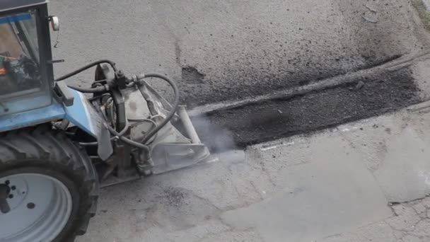 Ein Traktor schneidet eine Grubenmühle auf altem Asphalt. Straßenreparaturindustrie, Maschinen — Stockvideo