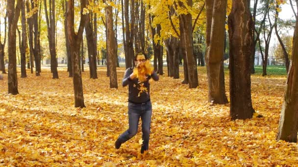 Jeune homme caucasien dans un masque drôle se réjouit en automne et jette des feuilles jaunes dans le ciel, fond, ralenti 
