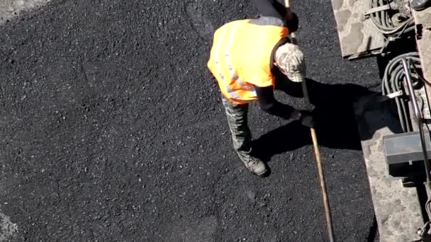 Trabajadores de la carretera ponen asfalto con palas y otros equipos especiales, reparación de carreteras, industria — Vídeos de Stock