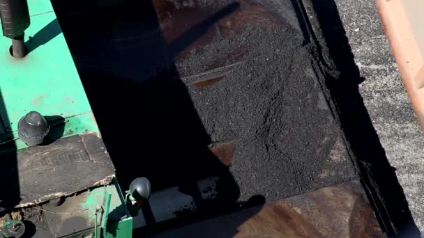 Um caminhão de descarga de carga derrama mistura de concreto asfáltico em um funil paver para reparação rodoviária, indústria. Equipamento rodoviário especial — Vídeo de Stock