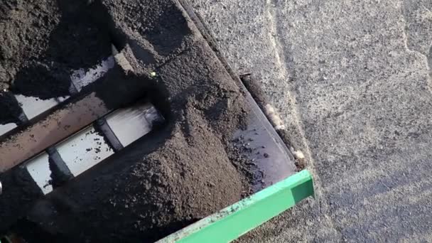 En asfaltläggare lägger ny asfalt ovanpå en gammal vägreparation. Särskild vägutrustning, industri, närbild — Stockvideo