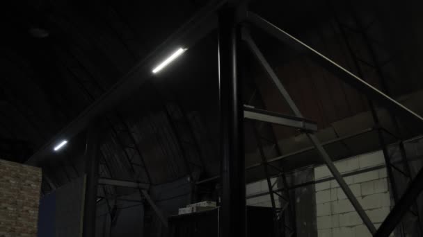 Luces led lámparas en vigas de metal particiones apagar y encender en el cuarto oscuro de la planta, hangar, departamento de taller sin ventanas. Fallo de energía, cortocircuito eléctrico de red en área industrial — Vídeo de stock