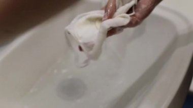 Kızlar salgın sırasında yeniden kullanılabilir koruyucu bir tıbbi yüz maskesi yıkarlar. Koronavirüs sırasında koruyucu maskelerin yeniden kullanılması.