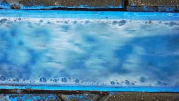 Вода течёт по голубой металлической дождевой канаве. Мощный поток сточных вод течет во время отлива, пространство для копирования текста — стоковое видео